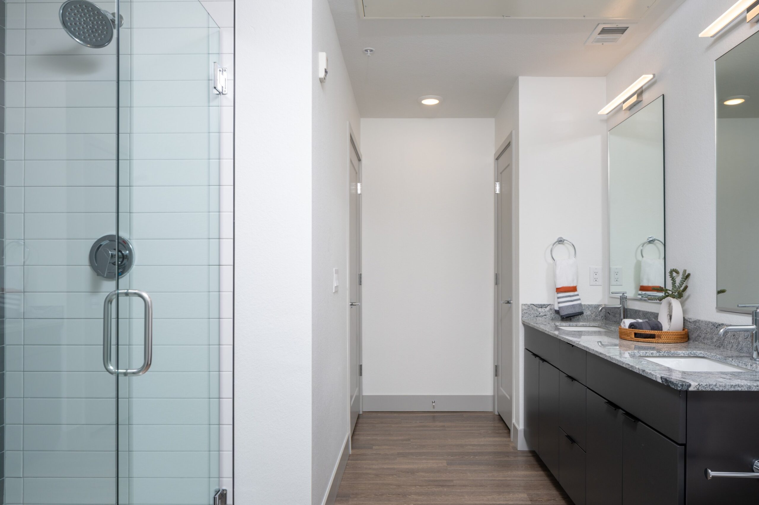 Model bathroom with his and hers sinks and tiled walk-in shower