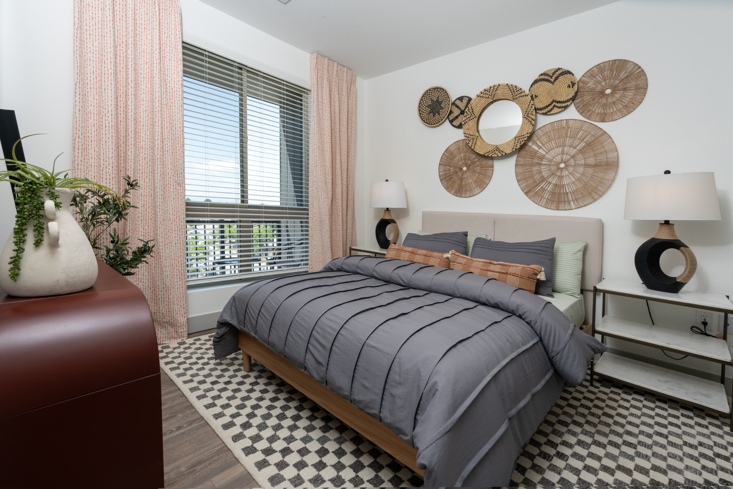Model bedroom with hardwood-style plank flooring and large window